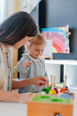 Fototapeta premium A smiling young woman and a little girl engage in a fun educational activity, playing with musical toys in a bright, cheerful indoor setting