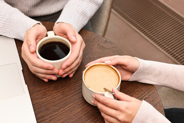 Colleagues having coffee break at wooden table in cafe, closeup