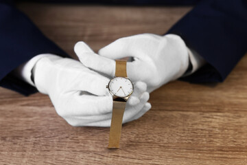 Appraiser with luxury wristwatch at wooden table, closeup