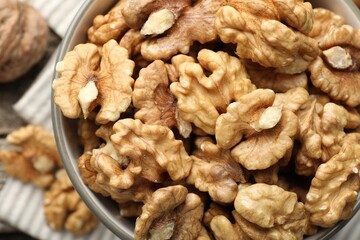 Fresh walnuts in bowl on table, top view