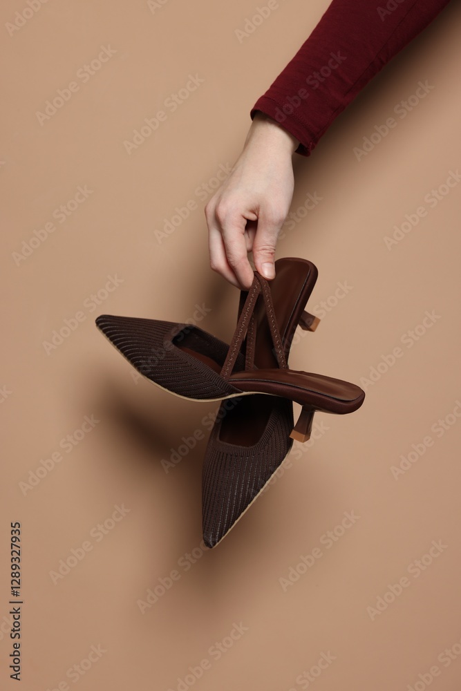 Canvas Prints Woman showing stylish high-heeled shoes on beige background, closeup