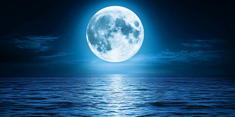 Full moon shining brightly over a tranquil ocean reflecting a silvery path on the water's surface under a deep blue night sky.