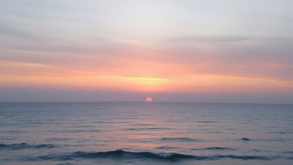 Obraz premium Soft pastel sunset over the calm ocean, with gentle hues of pink, purple, and blue blending in the sky. The tranquil scene captures the serene beauty of nature.