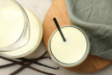 Delicious vanilla milk and pods on grey table, flat lay