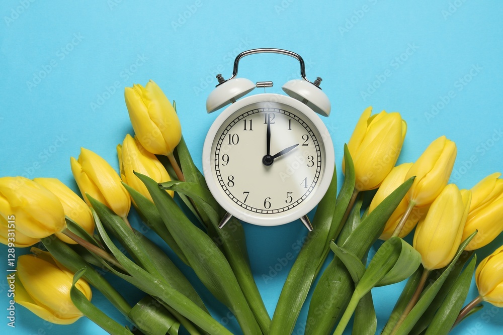 Poster spring time. alarm clock and beautiful tulips on light blue background, flat lay