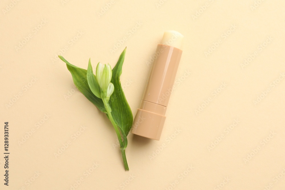 Sticker Lip balm and flower with leaves on beige background, top view