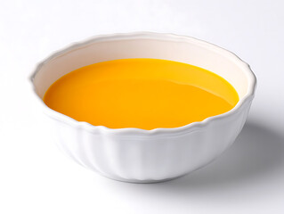 Smooth bright yellow soup fills a white fluted ceramic bowl sitting against a stark white background with soft shadow.