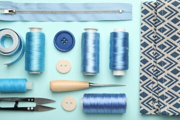 Different sewing supplies on light blue background, flat lay