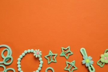 Cute hair accessories on orange background, flat lay. Space for text