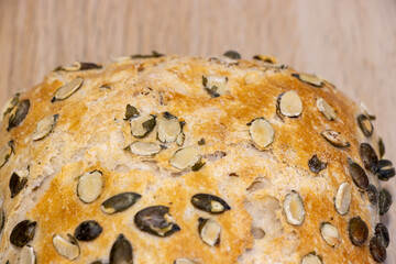Freshly baked bread with pumpkin seeds on a wooden background, showcasing a crispy crust and...