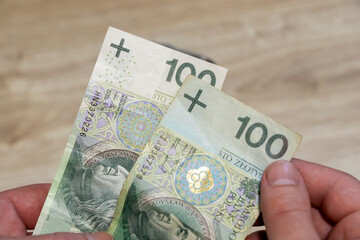Close-up of Polish banknotes being held, showcasing detailed design and vibrant colors. Ideal for finance, business, or economics themes.