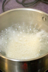 Steaming pot with boiling water and rice, symbolizing the cooking process. Ideal for culinary articles or cooking blogs.
