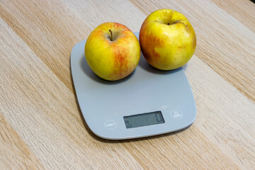 Two ripe apples on a digital scale. The image captures freshness and health, ideal for food-related projects, cooking blogs, and nutrition content.