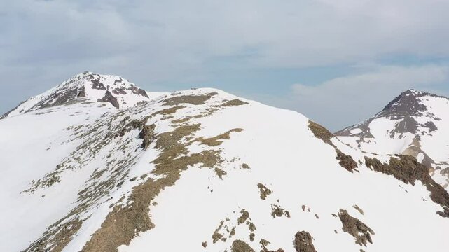 4K aerial drone footage of the snow-covered summits of Mount Aragats, the highest peak in Armenia, with its crater in spring. Breathtaking views of rugged highlands, glaciers, and remote wilderness.