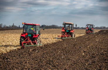 Fototapeta premium Tractors working on farmland during daytime in rural area