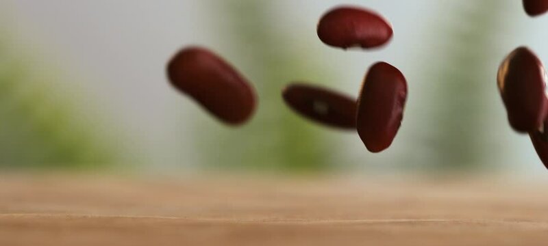 Macro close-up shot of red miki beans falling on wooden table from the above in slow-motion