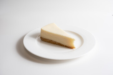 Traditional cheesecake on a white plate on a white background.