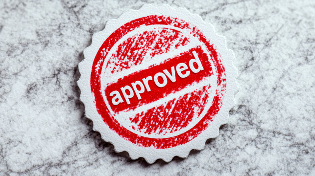 Red "approved" stamp on a textured gray surface. Concept of validation and acceptance. For business or office-related content.
