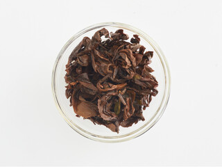 brewed tea leaves in a transparent cup, photo above on a white background