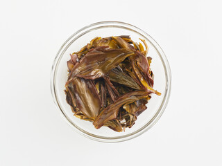 brewed tea leaves in a transparent cup, photo above on a white background