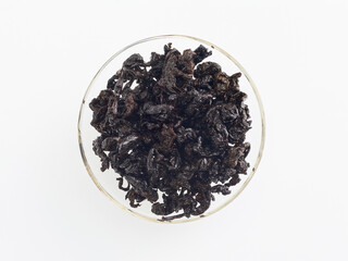 brewed tea leaves in a transparent cup, photo above on a white background