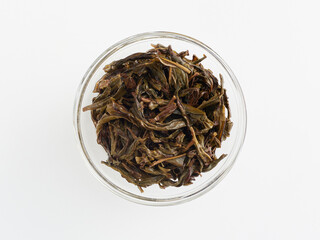 brewed tea leaves in a transparent cup, photo above on a white background