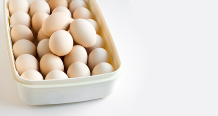 Many fresh, natural eggs in a bowl on a white surface with copy space