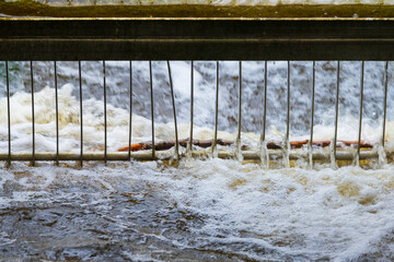 rushing water flowing through metal grate barrier.