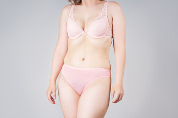 Skinny woman in pink lace lingerie on gray background