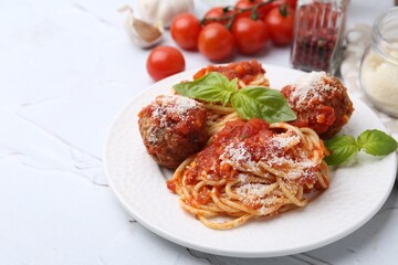 Delicious pasta with meatballs, basil and cheese on light textured table, closeup