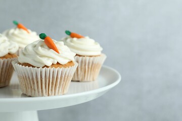 Delicious carrot cupcakes on stand against grey background, closeup. Space for text