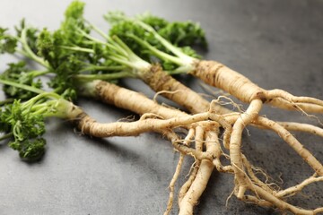 Parsley roots with leaves on black table, closeup