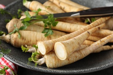 Parsley roots with leaves and knife on table, closeup