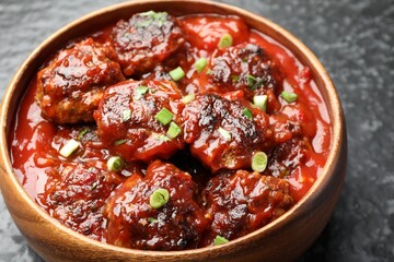 Delicious meatballs with tomato sauce and herbs on black table, closeup