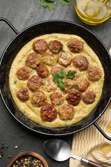 Delicious meatballs with gravy cream sauce and herbs served on black table, flat lay