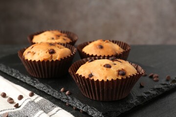 Delicious muffin with chocolate chips on black table, closeup