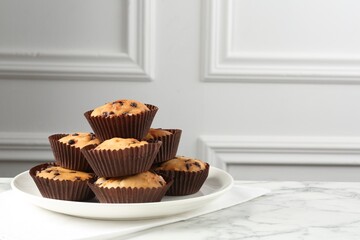 Delicious muffin with chocolate chips on white marble table, space for text