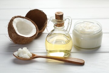 Organic coconut cooking oil, spoon and fresh fruit on white wooden table