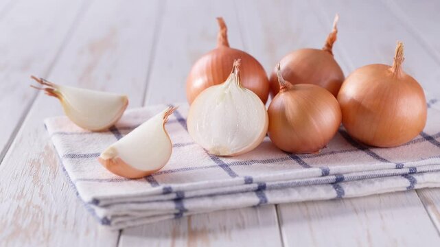 half an onion and a whole yellow onions on a light kitchen table. Yellow onions on a wooden table.
