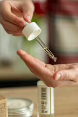 close-up of woman's hands with pipette and hand care oil. girl rubbing oil on palms, beauty,...