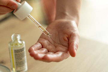close-up of woman's hands with pipette and hand care oil. girl rubbing oil on palms, beauty, cosmetology and skin care