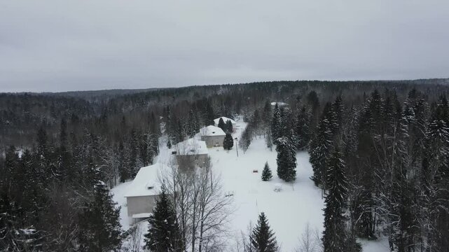 snow-covered residential buildings in winter in the north among the winter coniferous forest taken from a dro
