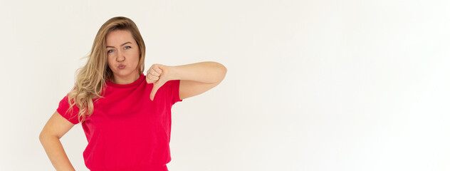 Young sad displeased unhappy woman wear red t-shirt showing thumb down dislike gesture isolated on...