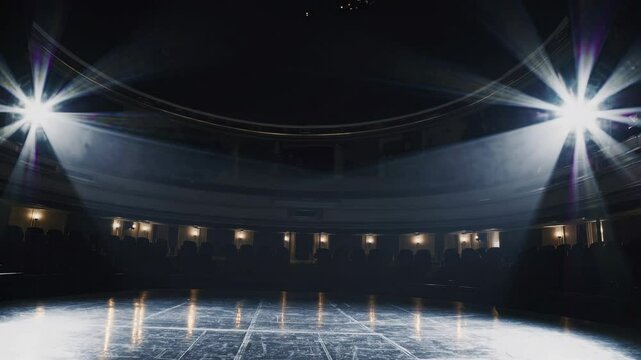 Low-angle video shot of an empty theater stage with dramatic lighting, capturing the grandeur and anticipation of a live performance setting.