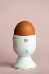 boiled chicken egg for breakfast. chicken egg in stand isolated on pink background, protein for breakfast
