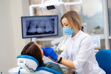 Dentist checks patient teeth. A dental professional wearing a mask and gloves examines a patient's...