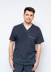 Obraz premium Health pro exudes warmth. Young man wearing scrubs poses with a smile, conveying warmth and approachability in a healthcare setting.