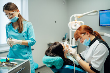 Dentists caring for patients. Two dental specialists attend to a patient during an appointment in a modern clinic, ensuring comfort and safety.