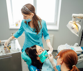 Dentist treating patient. A dental team provides care and treatment to a patient in a well-equipped...