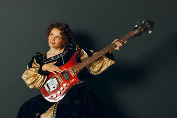 Obraz premium Portrait of a young adult woman playing music on electric guitar and dressed in a medieval dress